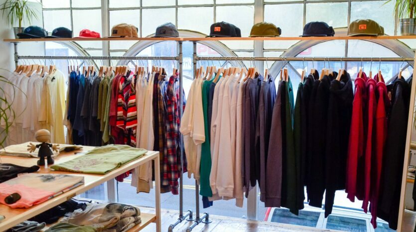 Retail shopping, clothes on a rack in a store with hats lined up on top